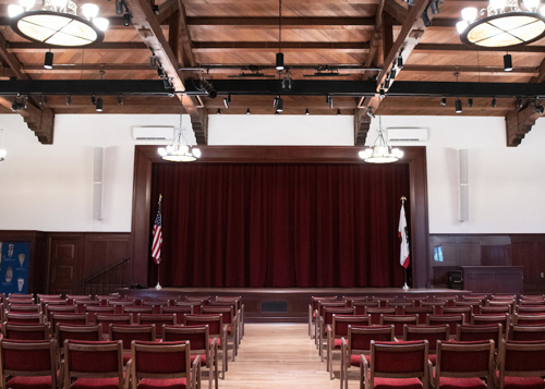 Fleischmann Auditorium stage with the curtain drawn and several rows of chairs.